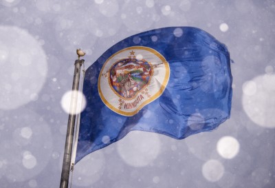 The current Minnesota flag, which lawmakers hope to soon retire, flies during a snowstorm.